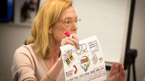 Sue J. Goldie holding up a drawing from the workshop.
