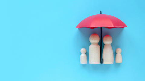 Wooden toy people underneath an umbrella, the symbol of universal health coverage.