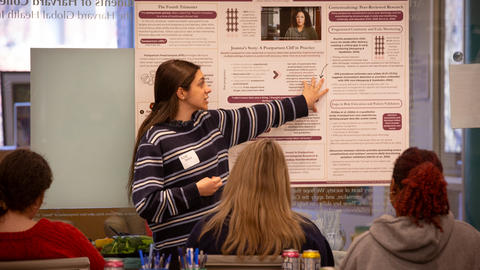 A student from GHHP20 gestures to their poster, presenting to their classmates.