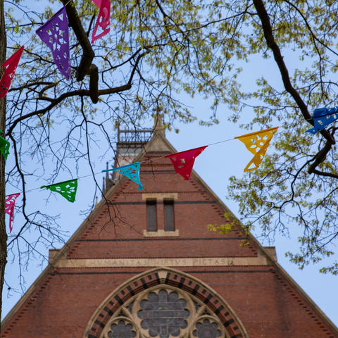 Colorful flags in front of a church roof.