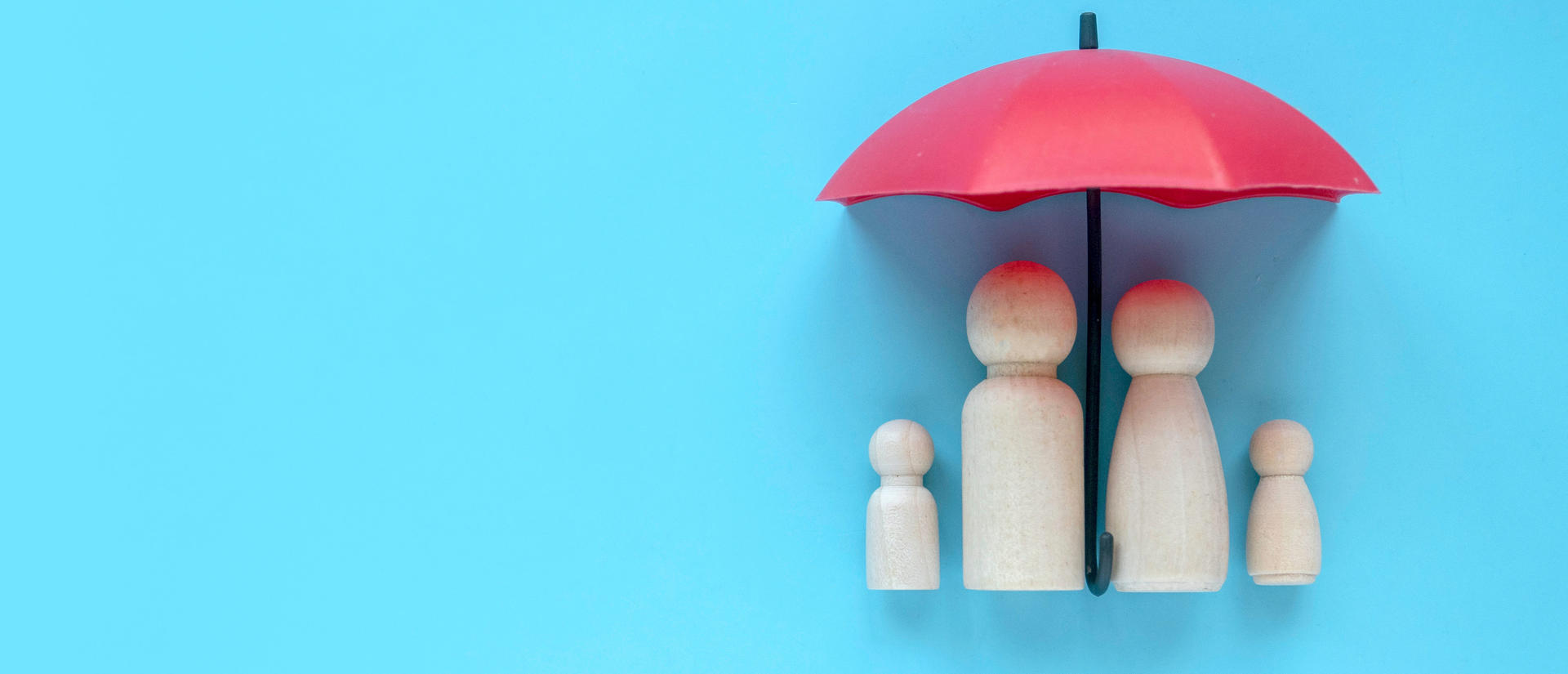 Wooden toy people underneath an umbrella, the symbol of universal health coverage.