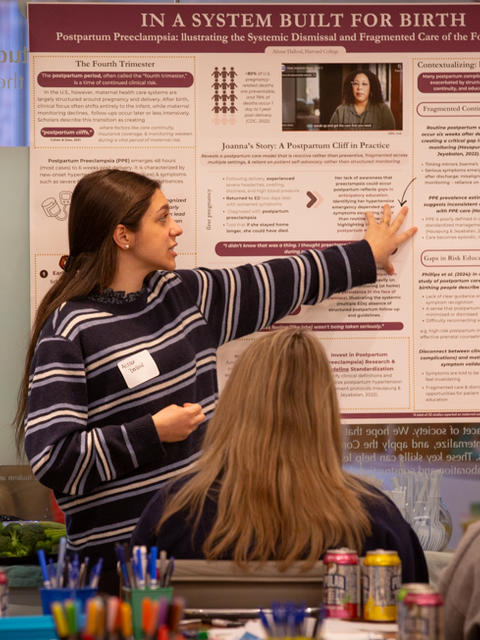 A student from GHHP20 gestures to their poster, presenting to their classmates.